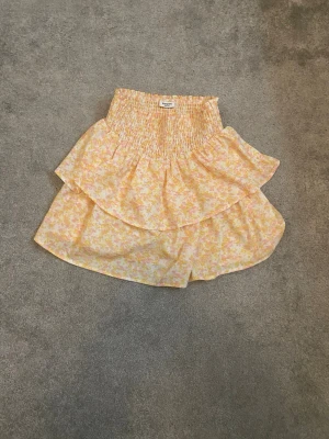 Blommiga volangshorts från Kappahl - Söta shorts från Kappahl med blommigt mönster i ljusgult och rosa. Modellen har hög smockad midja och dubbla volanger som ger en kjolliknande look. Perfekta för sommarens alla dagar.