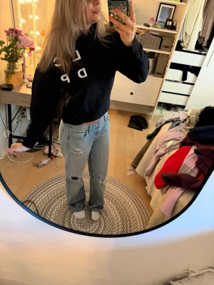Svart hoodie med vit text - Säljer en svart hoodie med vit text tryckt diagonalt över bröstet. Hoodien har en klassisk huva och en avslappnad passform. Perfekt för dig som gillar en enkel men ändå trendig stil. Materialet ser ut att vara mjukt och bekvämt.