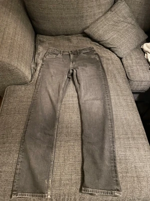Gråa raka jeans - Säljer ett par gråa jeans med rak passform och klassisk femficksdesign. Jeansen har normal midja och är tillverkade i ett mjukt denimtyg. Perfekta för en avslappnad och stilren look.