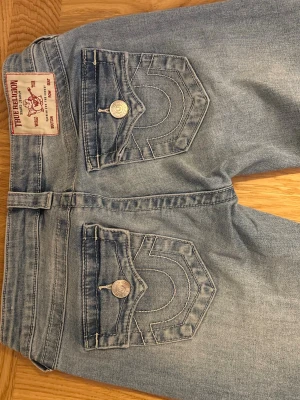True religion jeans - True religion jeans i modellen Joey low rise flare. Ljusblå fin färg med dekorerade bakfickor. Tyvärr lite upptrampade på baksidan av byxbenet men det är inget som stör när man har på sig jeansen. I övrigt gott skick. 