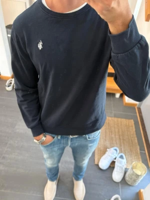 Mörkblå sweatshirt från polo - Mörkblå sweatshirt från us polo med rund halsringning och diskret logga broderad på bröstet. Tröjan har långa ärmar och ribbade muddar vid ärmslut och nederkant. Perfekt för en avslappnad och stilren look. Storlek L men passar mer en M/S modellen är 182 cm och 65 kg