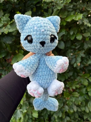 Virkad blå shark kitty🩵 - Supergullig virkat gosedjur i form av en blå katt med hajfenor. Tillverkad i mjukt plyschgarn med stora svarta ögon, vita och rosa detaljer på tassarna. Perfekt som present eller dekoration. Rekommenderar inte till småbarn eftersom ögonen utgör en kvävningsrisk!