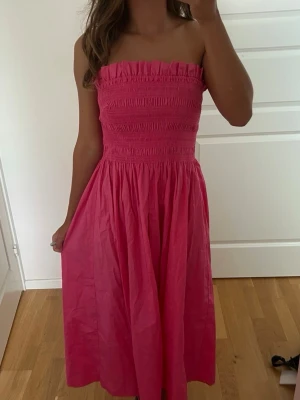 Axelbandslös rosa klänning - Säljer en söt axelbandslös rosa klänning från hm. Väldigt skön!!
