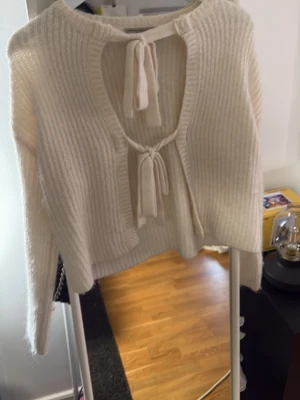 Vit ribbstickad kofta med knytband - Superfin vit ribbstickad kofta med två knytband framtill. Koftan har lång ärm och är gjord i ett mjukt, fluffigt material som känns riktigt cozy. Perfekt att slänga över en topp för en chill look.