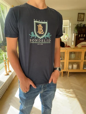 Mörkblå Bondelid t-shirt med tryck - Riktigt fet bondelid T-shirt med tryck! Storlek S. Har liten defekt (se bild 4), det är endast när man tittar riktigt noga som man ser den (inget man tänker på)😊Hör av dig vid funderingar!