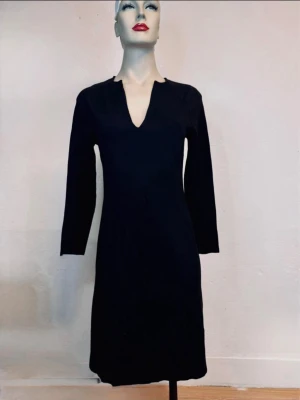 Filippa K Svart Klänning/Tunika Stl S – Minimalistisk Skandistyle - Stilren svart klänning från Filippa K i storlek S. Kan bäras både som klänning och tunika beroende på din längd och styling. Tidlös minimalistisk design med smickrande V-ringning och lång ärm som passar lika bra till sneakers som boots eller leggings. Fint vintageskick med normal patina från användning. Ett mångsidigt kvalitetsplagg som aldrig går ur stil. Jag erbjuder bundlerabatt vid köp av flera föremål.