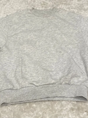 Ljusgrå basic sweatshirt - En enkel och stilren ljusgrå sweatshirt med rund hals och ribbade muddar vid ärmslut och nederkant. Perfekt oversized fit för en avslappnad look. Tillverkad i mjukt sweatshirtmaterial som känns skönt mot huden.