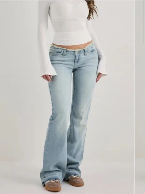 Ljusblå bootcut jeans med låg midja - Säljer ett par ljusblå bootcut jeans med låg midja och klassisk femficksdesign. Jeansen har en avslappnad passform och är tillverkade i denim med lätt tvättad look. Perfekta för en trendig och avslappnad stil.