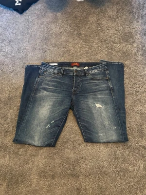 Blå slitna jeans  - Säljer ett par blå jeans med raka ben och slitna detaljer på framsidan. Jeansen har klassisk femficksdesign, normal midja och en snygg tvättad look. Priset är diskuterbart
