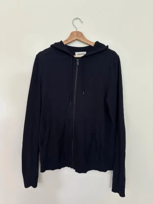 Zadig & Voltaire zip-hoodie, 100 % merinoull - Säljer en svart zip-hoodie från Zadig & Voltaire i 100 % merinoull. Klassisk och stilren modell med dragkedja och huva som passar både till vardag och mer uppklädda tillfällen. Tröjan är i fint begagnat skick och väl omhändertagen. Mjuk, bekväm och tillverkad i hög kvalitet.