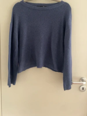 Blå oversized stickad tröja - Mysig blå stickad tröja med avslappnad, oversized passform och långa ärmar. Tröjan har en enkel design utan mönster och är tillverkad i ett mjukt, fluffigt material som känns skönt mot huden. Perfekt för kyliga dagar.