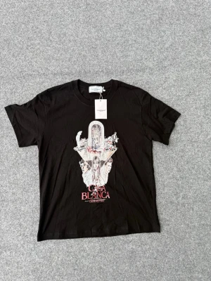 Svart Casa Blanca Grand Prix t-shirt - Svart t-shirt från Casablanca med ett stort grafiskt tryck på framsidan som föreställer tecknade personer och texten 'Casa Blanca Grand Prix'. Klassisk rund hals och korta ärmar. Perfekt för dig som gillar streetwear och unika prints.