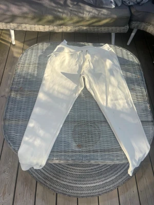 Vita mjukisbyxor från Polo Ralph Lauren - Säljer ett par vita mjukisbyxor från Polo Ralph Lauren med broderad logga på benet. Byxorna har dragsko i midjan och är gjorda i mjukt bomullsmaterial. Perfekta för chill dagar eller när du vill ha en clean och avslappnad look. Har en svart liten smutsfläck på benet. Som kan gå bort.