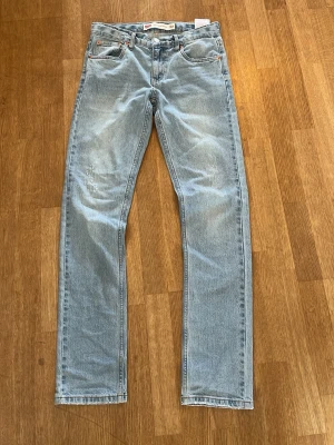 Ljusblå raka Levis jeans - Snygga ljusblå  Levis 512 slim taper jeans med rak passform och klassisk femficksdesign. Jeansen har en vintagekänsla med subtila slitningar och är tillverkade i denim. Perfekta för en avslappnad och trendig stil.
