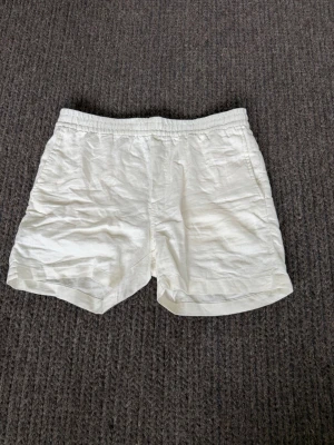 Vita linneshorts  - Snygga vita shorts i linne med avslappnad passform och resår i midjan. Shortsen har sidofickor fram och två dekorfickor bak. Perfekta för varma dagar och ger en fräsch och clean look.