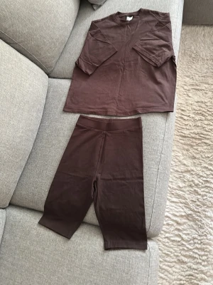 Brunt set från Divided H&M - Säljer ett brunt set från Divided H&M i storlek XXS.  Setet består av en kortärmad topp och cykelbyxor i stretchigt, mjukt material. Perfekt för en avslappnad och trendig look. Materialet är bomull och elastan för skön passform. Passar XS och S oxå.