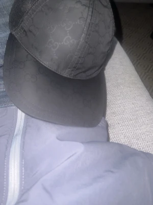 Svart keps med diskret GG-mönster - Snygg svart keps med diskret GG-monogram över hela kepsen. Klassisk böjd skärm och mesh på sidorna för extra ventilation. Perfekt accessoar för en trendig och avslappnad look.