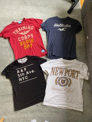 T-shirts - Säljer 4 feta tishor från hollister(L), superdry(L)och abercrombie & fitch (vitM) (svartS). Den röda från superdry, blåa från hollister, och den vita och svarta från a&f. Pris för 1=130, 2= 250, 3= 350, 4= 425. Han på bilden är 178 cm lång. De alla är i gott skick, har du frågor? Var inte rädd att höra av dig. 