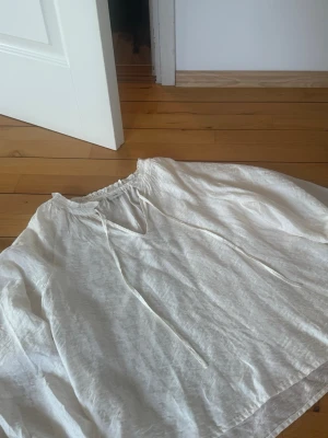 Vit blus med knytband från JDY - Luftig vit blus från JDY i storlek M. Blusen har långa ärmar, rundad halsringning med volangkant och knytband framtill. Tillverkad i ett tunt, lätt material som ger en avslappnad och trendig look.