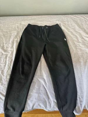 Ralph Lauren byxor - Säljer ett par svarta mjukisbyxor med dragsko i midjan och resår vid bensluten. Byxorna har en liten broderad logga på framsidan och en bakficka. Perfekta för chill dagar eller när du vill vara bekväm.