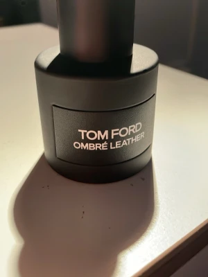 Tom Ford Ombré Leather parfym - Tom Ford Ombré Leather parfym i en stilren, matt svart flaska med tydlig vit text på etiketten. Flaskan har en rund form och känns lyxig och modern, perfekt för dig som gillar exklusiva dofter och snygg design. 47 ml kvar 