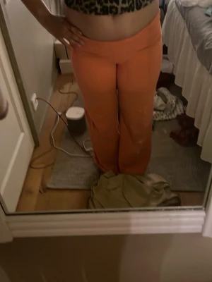 Vida coral mjukisbyxor - Säljer ett par mjukisbyxor i en snygg orange färg med hög midja och vida ben. Perfekta för chill dagar hemma eller när du vill ha en avslappnad stil. Mjukt och stretchigt material som sitter skönt på kroppen.
