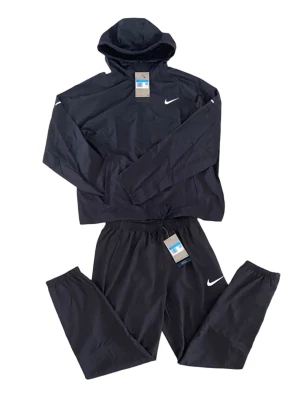 Nike Miller set - Snyggt svart träningsset från Nike med matchande hoodie och byxor. Setet har Nike-logga på både tröja och byxa, huva på tröjan och resår i midjan på byxorna. Materialet är lätt och andas bra. Storlek M. Perfekt för gym, träning eller vardagsoutfit.