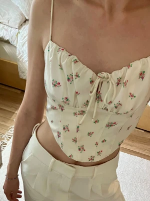 Vit blommig korsett topp - Korset topp i vit färg med tunna axelband och små rosa blommor 😇
