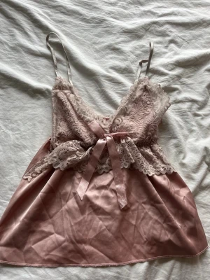 Rosa spetslinne med rosett - Rosa spetslinne med rosett. Obs rosetten är lite sliten. Storlek XS/S