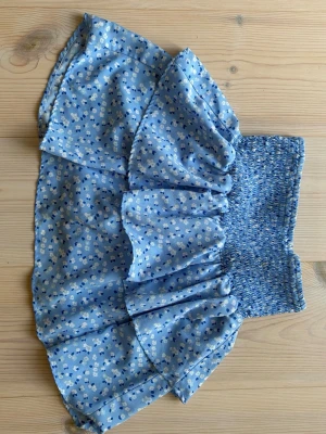 Blå blommig volangkjol - Jätte söt blå kortkjol med små vita och mörkblå blommor. Kjolen har volanger och passar bra runt midjan. Ganska säker på att den är från Zara eller Subdude. Går även att använda som en söt topp.🌊