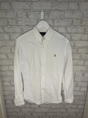 Ralph Lauren skjorta - Ralph Lauren Oxford-skjorta i klassiskt vitt med broderad logga och slim fit-passform. Skön kvalitet i lite kraftigare bomull som ger en riktigt fin känsla. Väldigt fint skick. Hör gärna av dig vid intresse! 🙌