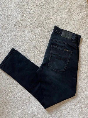 Svarta jeans från Nudie Jeans - Ett par väldigt snygga jeans ifrån märket Nudie Jeans. Storleken är 32-30 och modellen är Grim Tim. Jeansen har en snygg passform! Har du nån fråga eller fundering, skriv då!  😁✌🏼 ——————————————————————————                                                                      📐| Storlek: 32-30                                                  👖| Märke: Nudie jeans                                         🔎| Skick: Fint skick!                                               💵| Ny Pris: 1699kr          