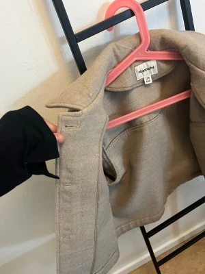 Beige jacka från Kappahl - Säljer en beige jacka från Kappahl i klassisk modell. Jackan har krage, knappar framtill och två sidofickor. Inga skador osv! Använd fåtal gånger!