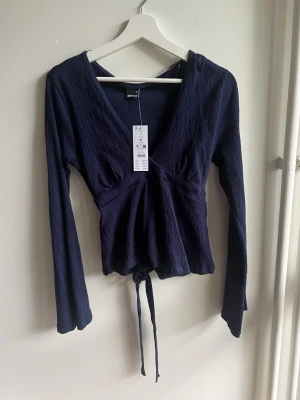 Mörkblå topp Gina Tricot - mörkblå topp från Gina Tricot med lång ärm och knyt i midjan