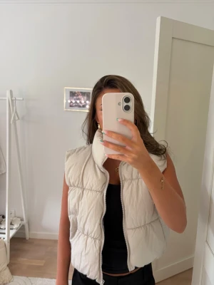 Beige puffad dunväst med hög krage - Snygg beige dunväst med puffad design och hög krage. Västen har dragkedja framtill och två fickor på sidorna.❤️❤️den kommer ifrån H&M och är i storlek M men skulle säga att den är mer en xs eller s.