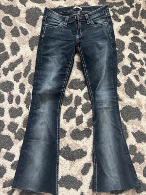 Bootcut jeans med broderade bakfickor - Snygga mörkblå lågmidjade bootcut jeans, dom är från Gina 14+ avdelningen i storlek S. Dom är klippta nertill så passar någon runt 160-163. 