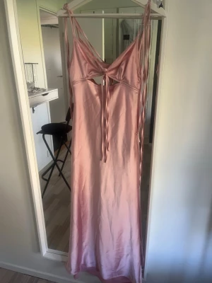 Zara klänning - Säljer en elegant ljusrosa långklänning i satinliknande material. Klänningen har smala axelband, snörningsdetalj framtill och öppen rygg med snygg cut-out. Perfekt för sommarens alla tillfällen! Har bara en defekt se bild 3, men inget större som man inte kan laga!!!!!