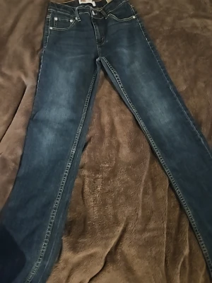 Levi's 511 Slim mörkblå jeans - Säljer ett par Levi's 511 Slim jeans i mörkblå denim. Jeansen har klassisk femficksdesign, smal passform och snygga kontrastsömmar. Perfekta för dig som gillar en modern och stilren look. Materialet är slitstark bomullsdenim.