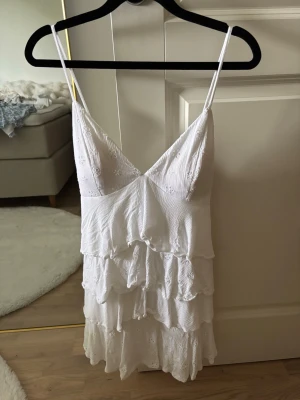 Vit volangklänning - Jättefin vit volangklänning med snörning i bak från Hollister i storlek S. Den har smarta fickor i längs sidan som är i princip osynliga. Kontakta gärna för mer info 🥰🥰
