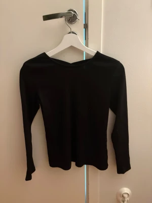 Svart långärmad topp från Lindex - En svart långärmad topp från Lindex med enkel och stilren design. Toppen har rund halsringning och är tillverkad i ett mjukt material som passar perfekt till många olika outfits. Stor i storleken sitter som en 164-170