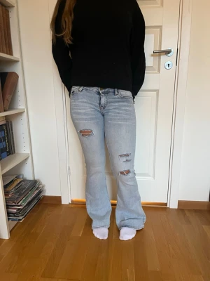Ljusblå jeans Cheap Monday - Säljer ett par lågmidjade ljusblå bootcut jeans från Cheap Monday i storlek 27/30. Slitna detaljer på framsidan. Priset går att diskutera