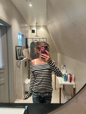Randig offshoulder långärmad topp - Säljer en svartvit randig offshoulder topp med långa ärmar. Toppen har en avslappnad passform och är perfekt för dig som gillar en chill och trendig stil. Materialet känns mjukt och skönt mot huden.