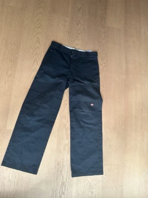 Svarta cargobyxor från Dickies - Svarta cargobyxor från Dickies med raka ben och klassisk passform. Byxorna har flera fickor, inklusive en sidoficka med Dickies-logga. Tillverkade i slitstarkt material. storköket 31/32