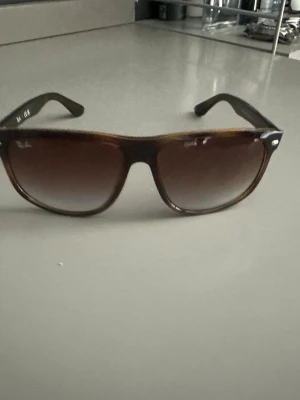 Bruna solglasögon från Ray-Ban - Snygga solglasögon från Ray-Ban med klassisk wayfarer-form. Bågarna är bruna med en lätt transparent finish och glasen är tonade i brunt. Perfekta för soliga dagar och ger en cool vibe till din outfit.