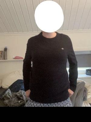 Mörkblå stickad tröja med brodyr - Mysig mörkblå stickad tröja med rund halsringning och diskret broderad detalj på bröstet. Tröjan har långa ärmar och enkel, klassisk design som passar till det mesta. Perfekt för kyligare dagar. Liten i storlek. Jag har storlek S och den passar bra.
