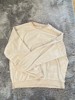 Beige oversized sweatshirt - En stilren beige sweatshirt med rund hals och långa ärmar. Tröjan har en avslappnad, oversized passform och ribbade muddar vid ärmslut och nederkant. Perfekt för en chill och enkel look.