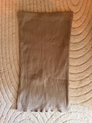 Beige ribbad kjol - Säljer en beige ribbad kjol med rak passform och stretchigt material. Kjolen är enkel och stilren, perfekt att matcha med en crop top eller oversized tröja. Midilängd och mjuk känsla.