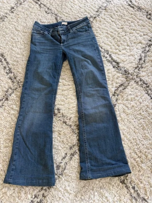 Blå bootcut jeans från Nelly - Snygga blå bootcut jeans från Nelly med klassisk femficksmodell och normalhög midja. Jeansen har en lätt utsvängd passform nedtill och är gjorda i ett mjukt denimtyg. Perfekta för dig som gillar en retroinspirerad look. JEANSEN ÄR ÄVEN UPPSYDDA UNGEFÄR 5 CM
