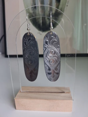 Silvriga ovala örhängen med mönster rostfritt stål  - Säljer ett par örhängen i oval form som är återbrukade av en tång I rostfritt stål/stainless Steel. Perfekta för dig som gillar unika accessoarer med lite boho-vibe. Öronkroken är nickelsäker. Längd ca 5cm långa 