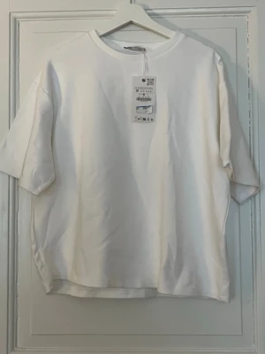Vit oversized t-shirt - Säljer en vit oversized t-shirt med rund hals och korta ärmar. T-shirten har en enkel och clean design, perfekt för en avslappnad stil. Tillverkad i mjuk bomull som känns skön mot huden. Nypris är 259kr.